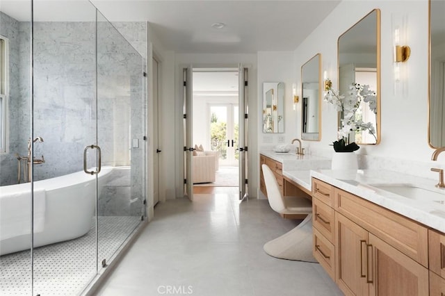 bathroom featuring double vanity, a shower stall, and a sink