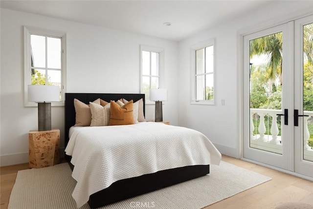 bedroom with access to exterior, light wood-style flooring, and baseboards