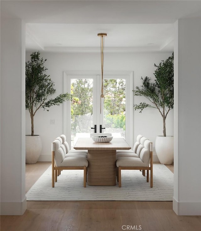 dining space with wood-type flooring and baseboards