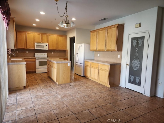 kitchen featuring white appliances, a sink, a kitchen island, light countertops, and decorative backsplash