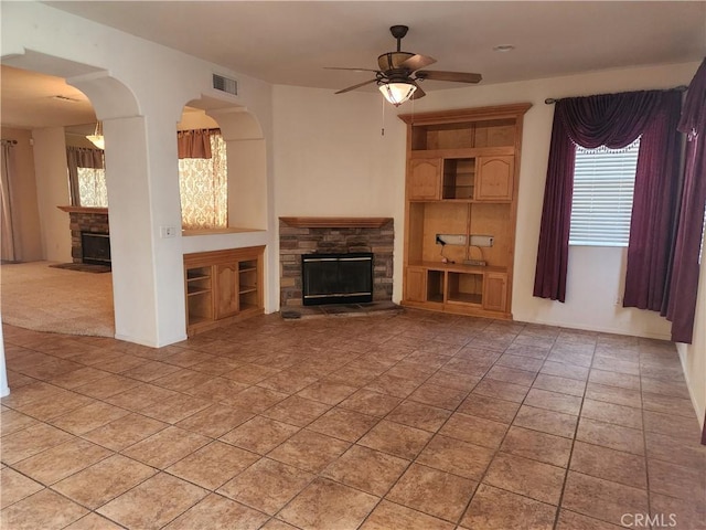 unfurnished living room featuring ceiling fan, light tile patterned floors, a fireplace, and visible vents