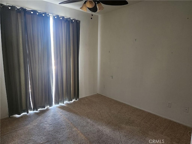 carpeted spare room with plenty of natural light and a ceiling fan