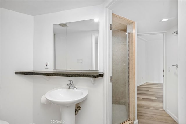 bathroom with a shower stall and wood finished floors