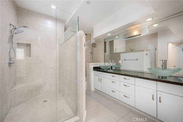 full bath featuring double vanity, a stall shower, a sink, and tile patterned floors