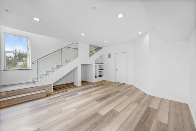 unfurnished living room with baseboards, stairway, and wood finished floors