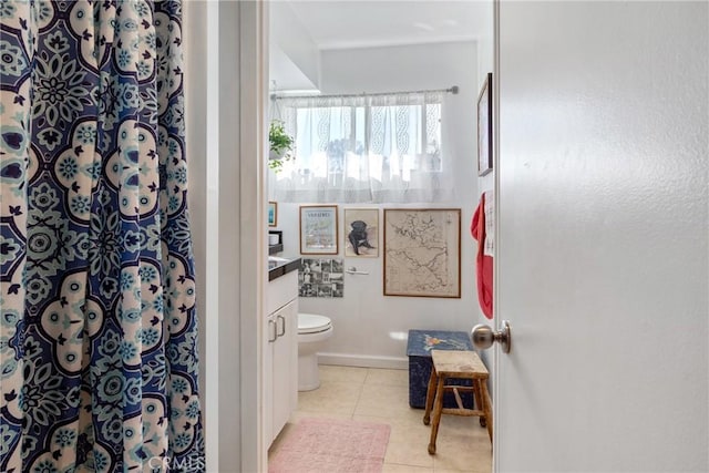 bathroom with tile patterned flooring, toilet, vanity, baseboards, and a shower with curtain