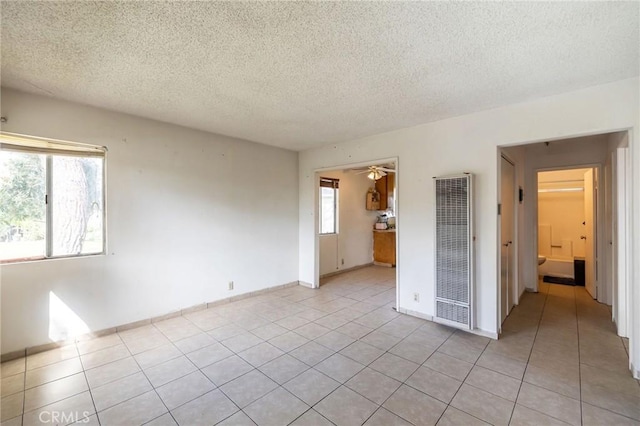 unfurnished room with a wealth of natural light, a heating unit, and light tile patterned flooring