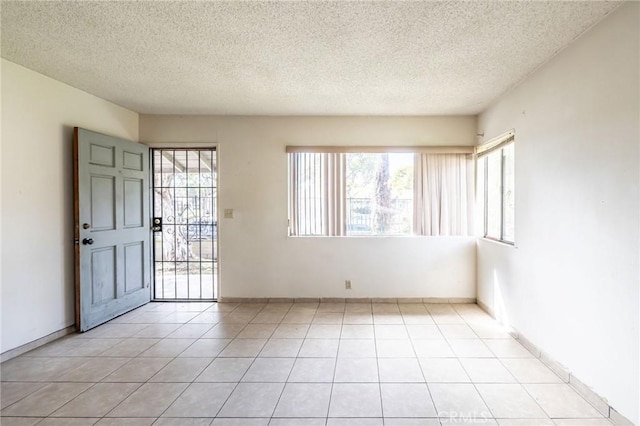 spare room featuring a wealth of natural light, light tile patterned flooring, and a textured ceiling