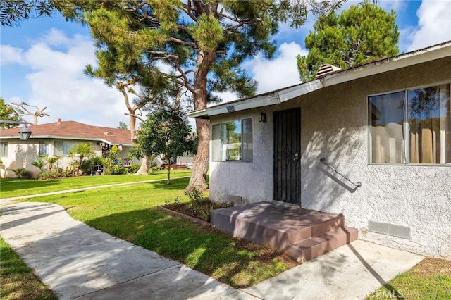 property entrance featuring a yard and stucco siding