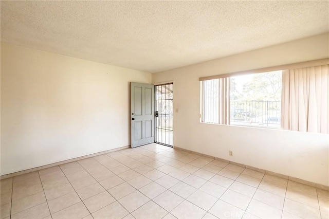 unfurnished room with a textured ceiling and light tile patterned floors