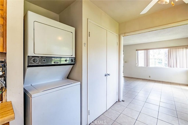 washroom with ceiling fan, laundry area, light tile patterned flooring, and stacked washer and clothes dryer