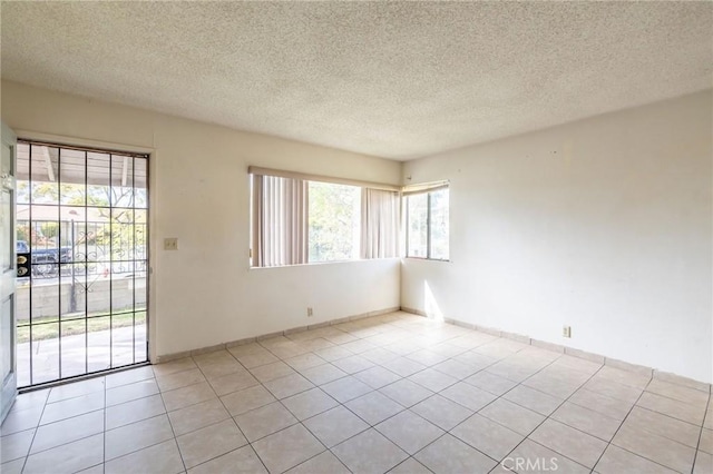 spare room featuring light tile patterned flooring and a textured ceiling