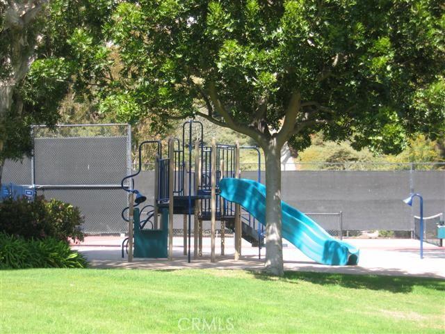 communal playground featuring a yard and fence