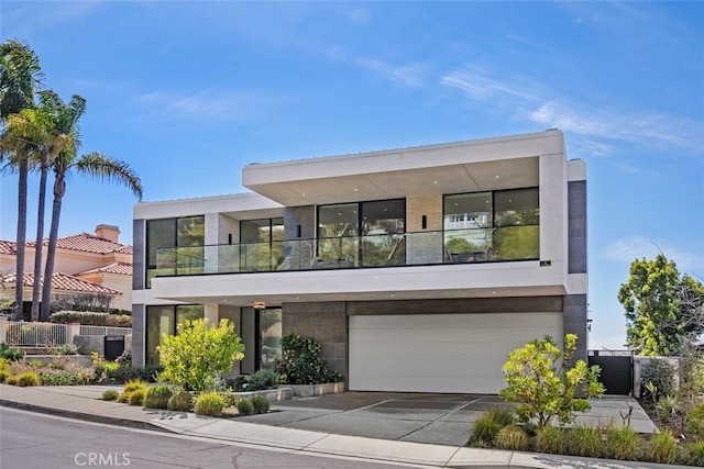 contemporary home with a garage, a balcony, concrete driveway, and stucco siding