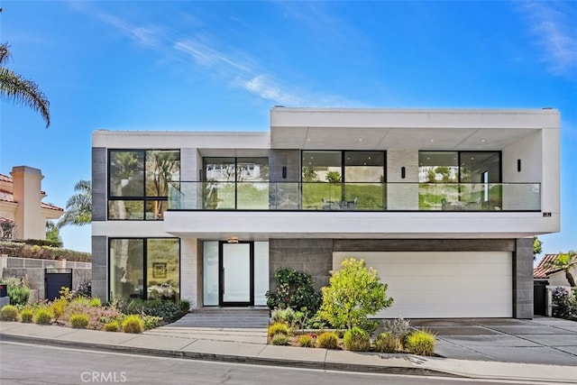 view of front facade featuring a garage, concrete driveway, and a balcony