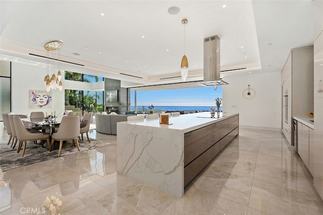 kitchen featuring marble finish floor, modern cabinets, island exhaust hood, and decorative light fixtures