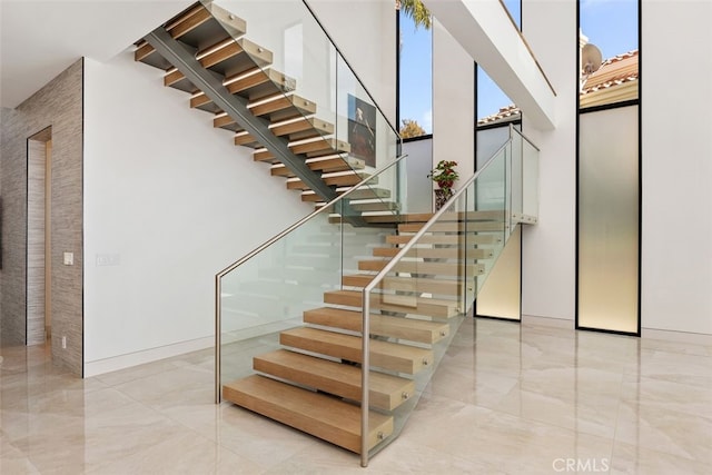 staircase with marble finish floor and a high ceiling