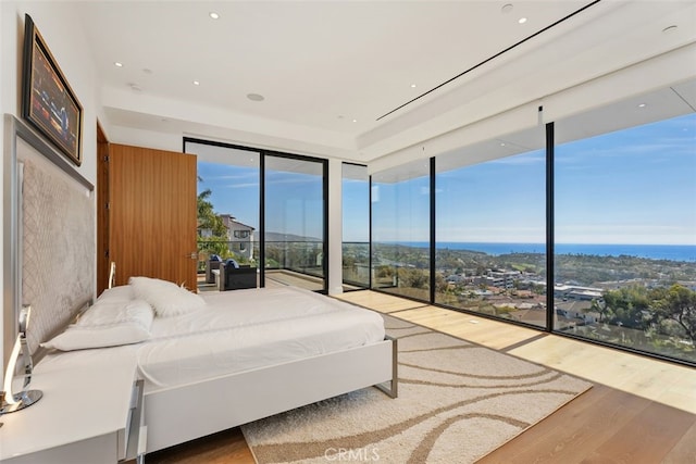 bedroom with expansive windows, access to outside, multiple windows, and wood finished floors