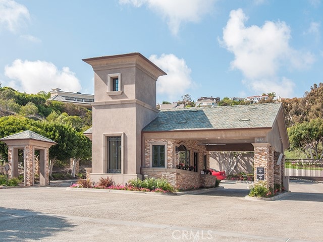 view of front facade with stone siding, fence, driveway, and stucco siding