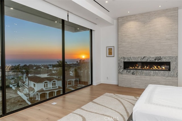 bedroom featuring floor to ceiling windows, baseboards, wood finished floors, and a high end fireplace