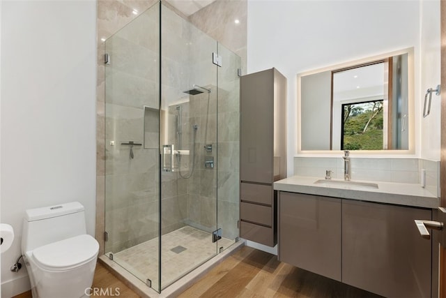 bathroom with vanity, a stall shower, wood finished floors, and toilet