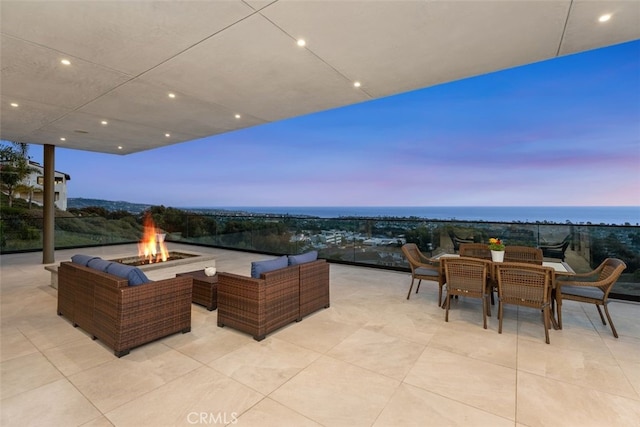 patio terrace at dusk featuring outdoor dining area and an outdoor living space with a fire pit