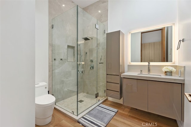 full bath featuring toilet, a shower stall, wood finished floors, and vanity