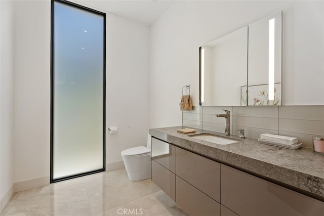 bathroom featuring toilet, vanity, baseboards, decorative backsplash, and tile patterned floors