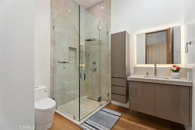 bathroom featuring toilet, a shower stall, wood finished floors, and vanity