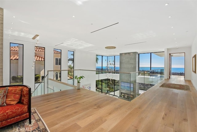 interior space with a water view, floor to ceiling windows, wood finished floors, and recessed lighting