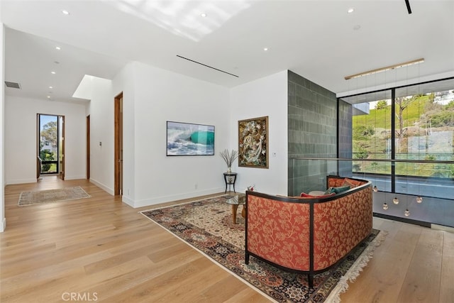 sitting room featuring baseboards, visible vents, light wood-style floors, floor to ceiling windows, and recessed lighting