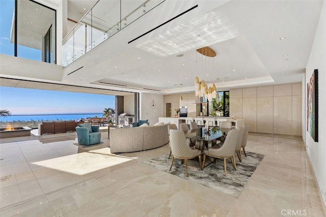 dining area featuring a tray ceiling, a water view, and a healthy amount of sunlight