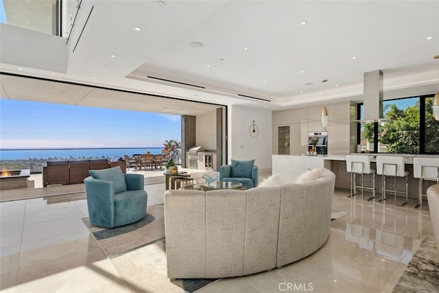 living room featuring a tray ceiling, a water view, recessed lighting, and a healthy amount of sunlight