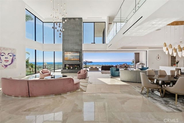 living area with a notable chandelier, a fireplace, marble finish floor, and a towering ceiling