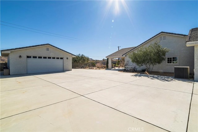 view of home's exterior featuring a garage, an outbuilding, stucco siding, and central air condition unit