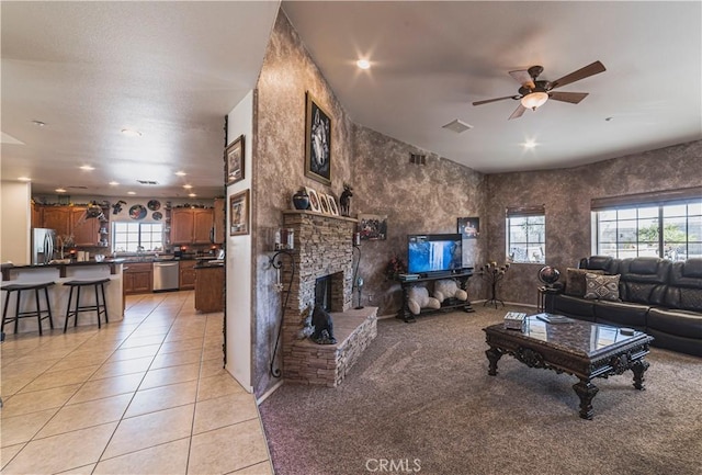 living area with light tile patterned floors, visible vents, a ceiling fan, a fireplace, and recessed lighting