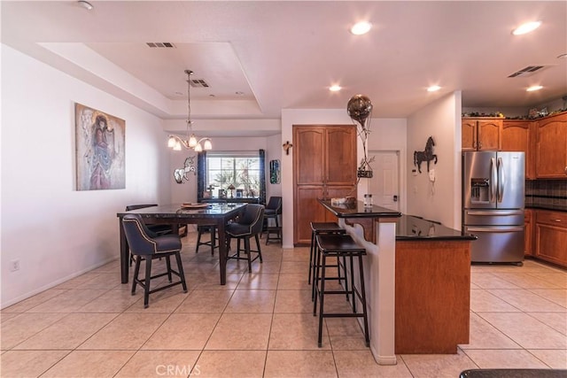 kitchen featuring dark countertops, light tile patterned floors, stainless steel refrigerator with ice dispenser, and visible vents