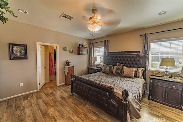 bedroom featuring a ceiling fan, baseboards, visible vents, and wood finished floors