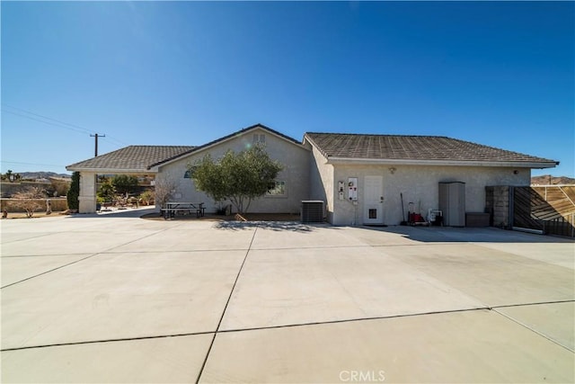 view of front facade featuring a tiled roof, stucco siding, and central air condition unit