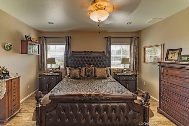 bedroom featuring light wood finished floors, multiple windows, visible vents, and baseboards