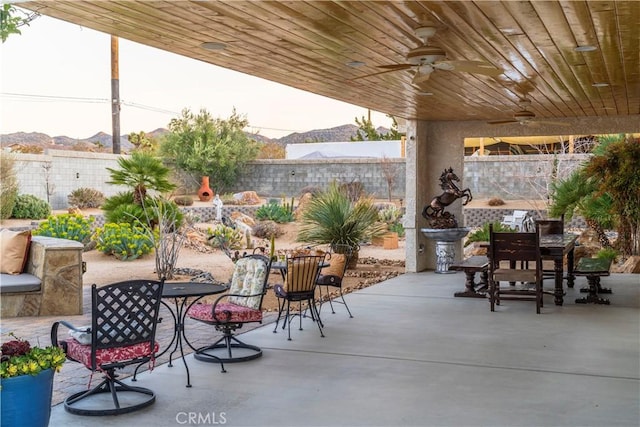 view of patio featuring a fenced backyard, a mountain view, a ceiling fan, and outdoor dining space