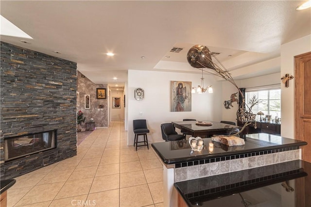 interior space with light tile patterned flooring, recessed lighting, a fireplace, visible vents, and a raised ceiling