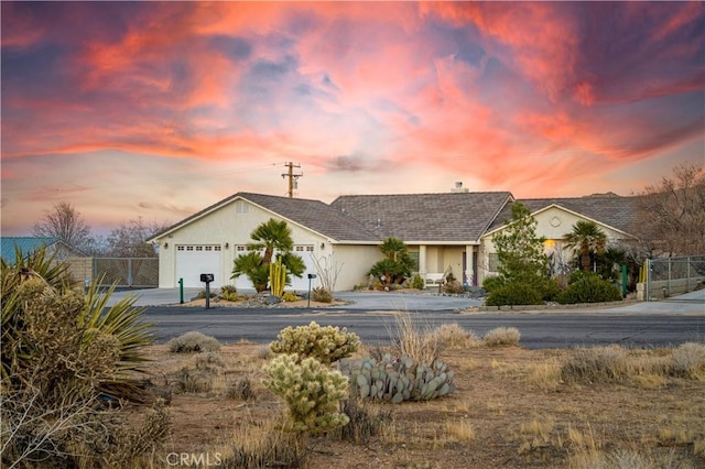 single story home featuring driveway, an attached garage, fence, and stucco siding