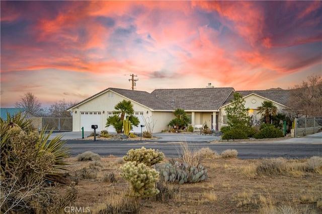 ranch-style house featuring stucco siding, an attached garage, concrete driveway, and fence