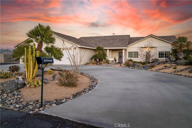 ranch-style home with driveway, a garage, and stucco siding