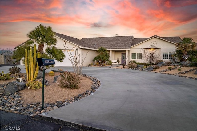 ranch-style house featuring stucco siding, curved driveway, and a garage