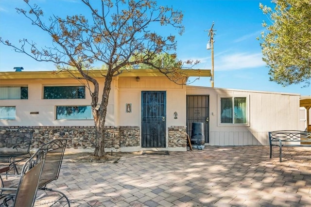 exterior space featuring stone siding and a patio area