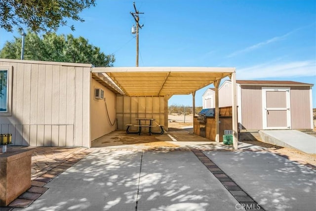 view of patio / terrace featuring a carport, an outbuilding, driveway, and a storage unit