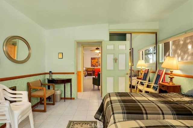 bedroom featuring light tile patterned floors, a closet, and wainscoting