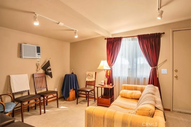 living area featuring rail lighting, beam ceiling, and an AC wall unit